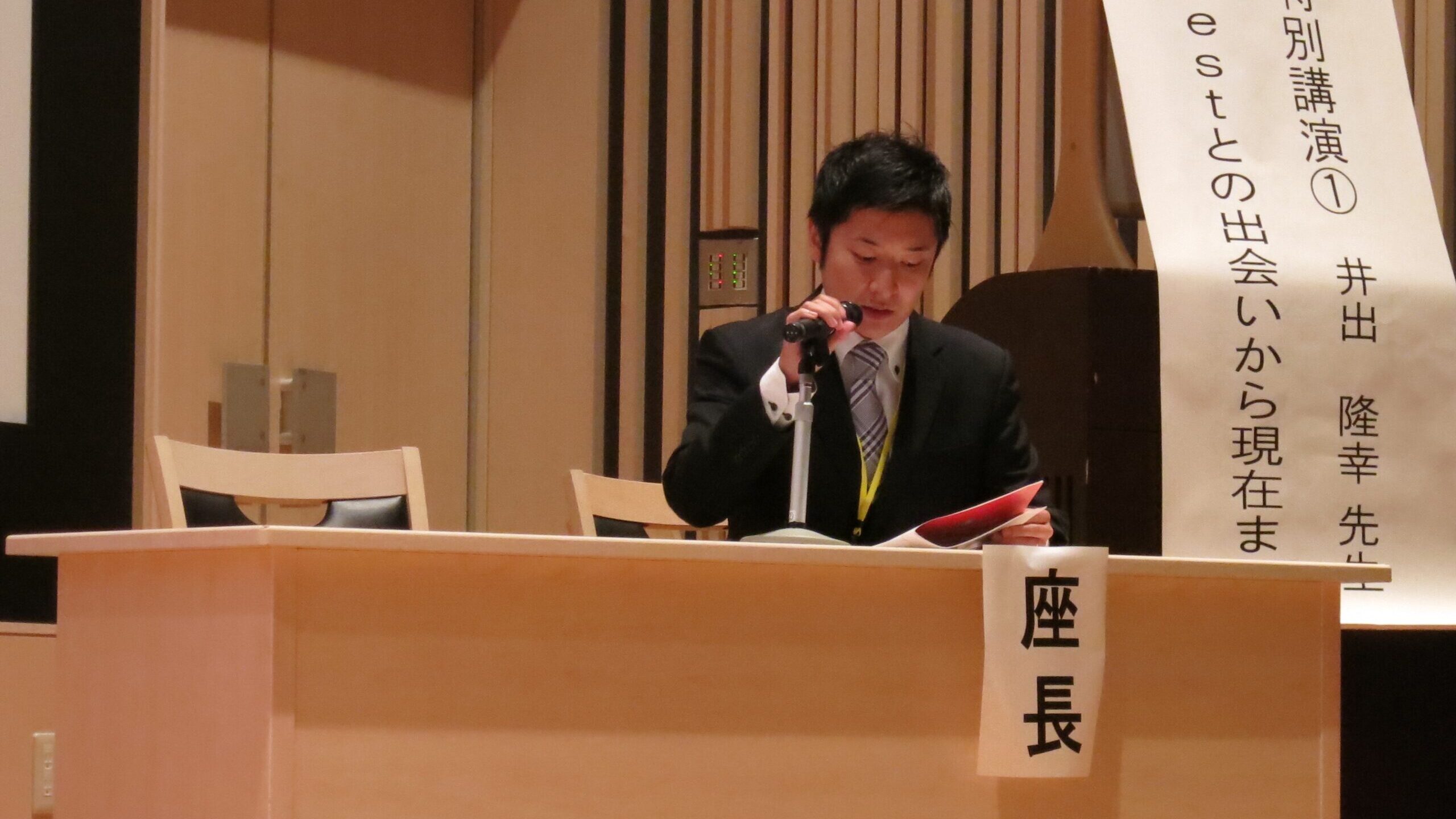 学会での座長風景。実際の臨床データをもとに、未来の施術者に対して丁寧に講義する場面。学術現場での登壇実績を象徴。